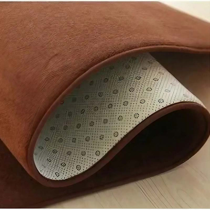 Brown textured rug with a patterned backing on a wooden floor.