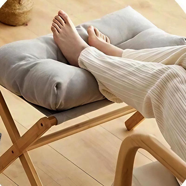 Grey cushioned wooden footrest used as a leg support, showcasing soft padding and natural wood frame, ideal for relaxation in modern homes.