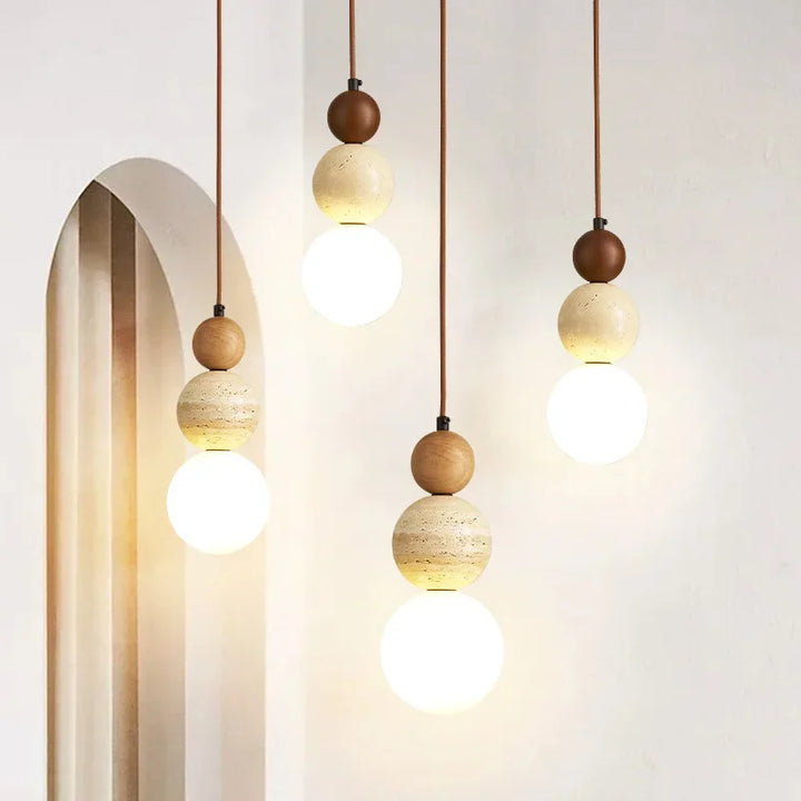 Trio of cream globe pendant lamps with stone and wood detail in warm interior décor