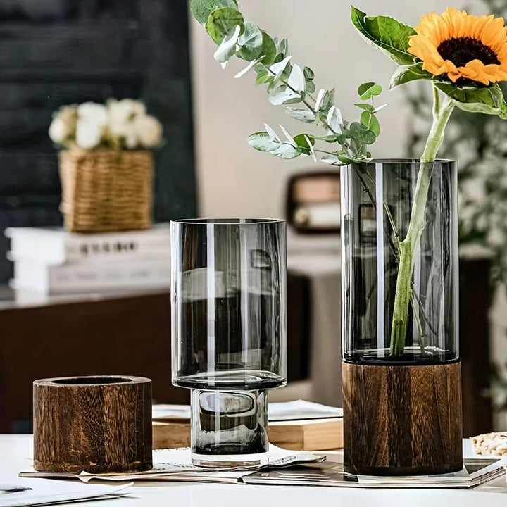 Smoked glass vase with warm wood base styled with roses and eucalyptus – Nordic-inspired table decor.