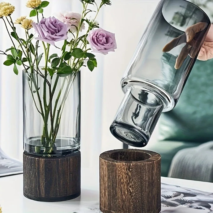 Dark tinted glass propagation vase being removed from solid wood base, ideal for minimalist interiors.