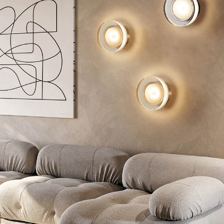 Set of ILD glass wall sconces arranged above sofa, creating a soft layered lighting effect in modern living room.