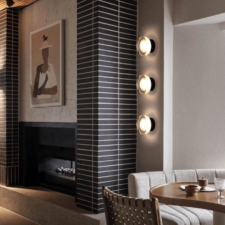 Modern wall sconces in column formation on dark vertical panel wall, creating accent lighting in modern UK lounge.
