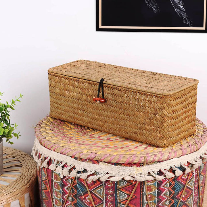 Lidded seagrass basket with toggle closure on decorative drum table, stylish natural storage for bedrooms or living spaces.