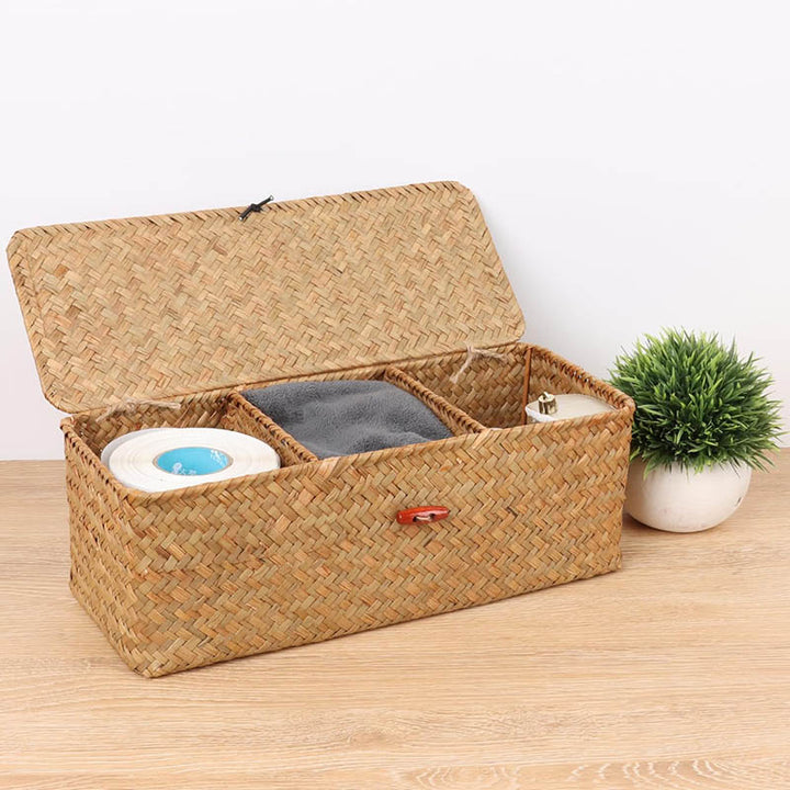 Open seagrass storage box with compartments holding toilet paper, towel and soap, ideal for eco-conscious bathroom storage.