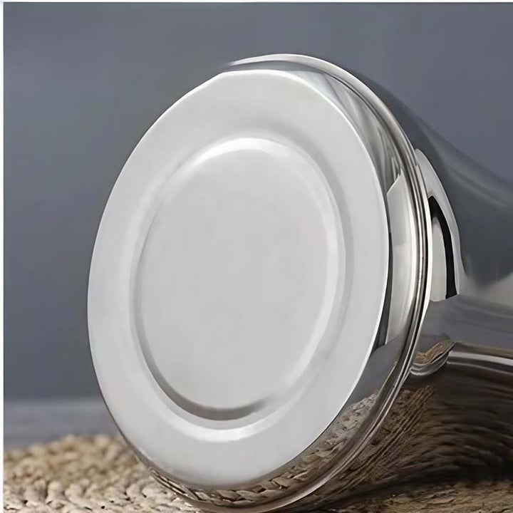 Close-up of a Silver stainless steel induction kettle with a reflective surface on a textured surface.