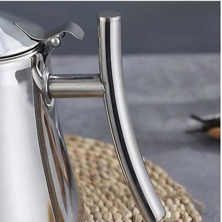Close-up of a shiny Silver stainless steel induction teapot handle on a textured surface with a blurred background