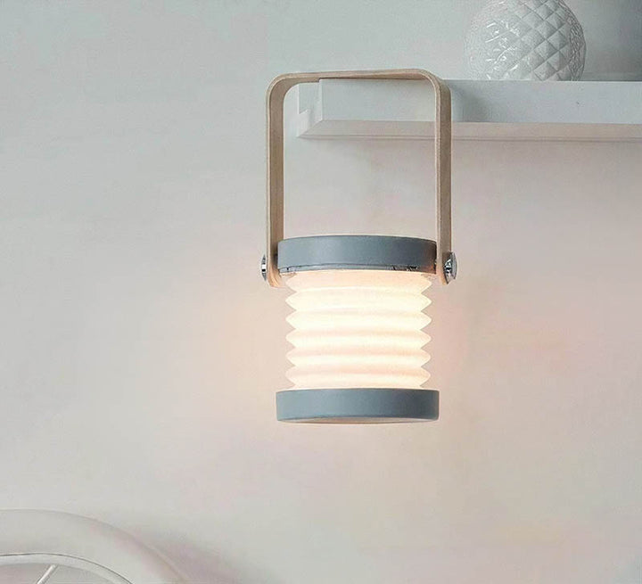 LYKT lantern glowing on a shelf with soft white accordion base extended for ambient lighting.