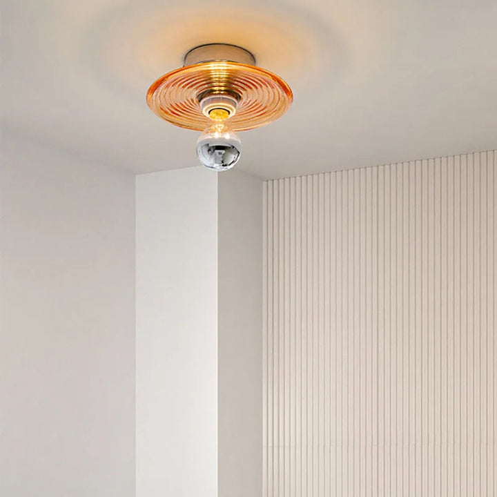 Ceiling light fixture with a gold and glass design on a neutral wall.
