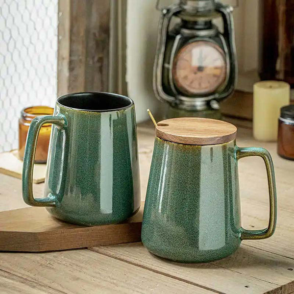 Two green ceramic mugs with wooden lids on a wooden surface.