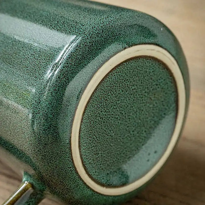Close-up of a green ceramic pot with textured surface on a wooden surface