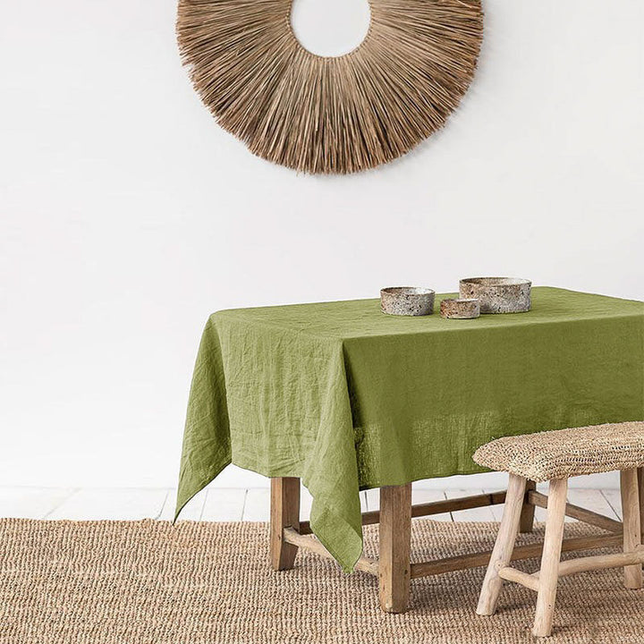 Light-green Linen tablecloth on a wooden table with decorative elements in a room setting.