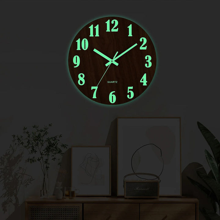 Glowing wall clock on a dark wall with decorative items below.