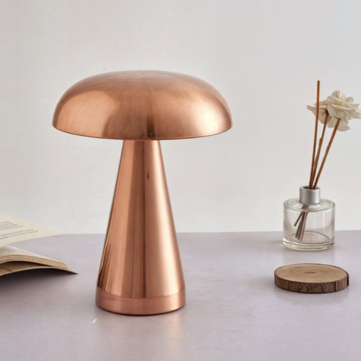Brushed copper rechargeable table lamp styled on desk beside book and reed diffuser.