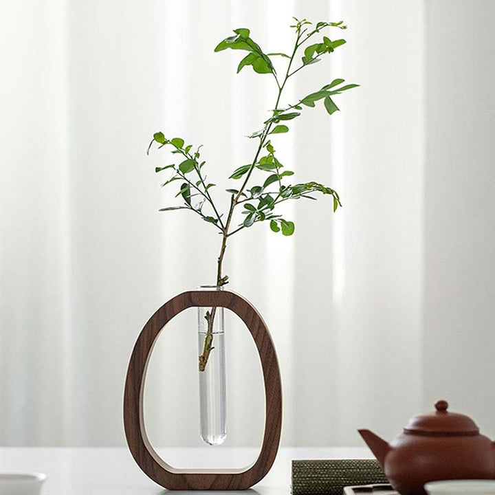 Vase with a plant on a wooden stand against a white curtain background