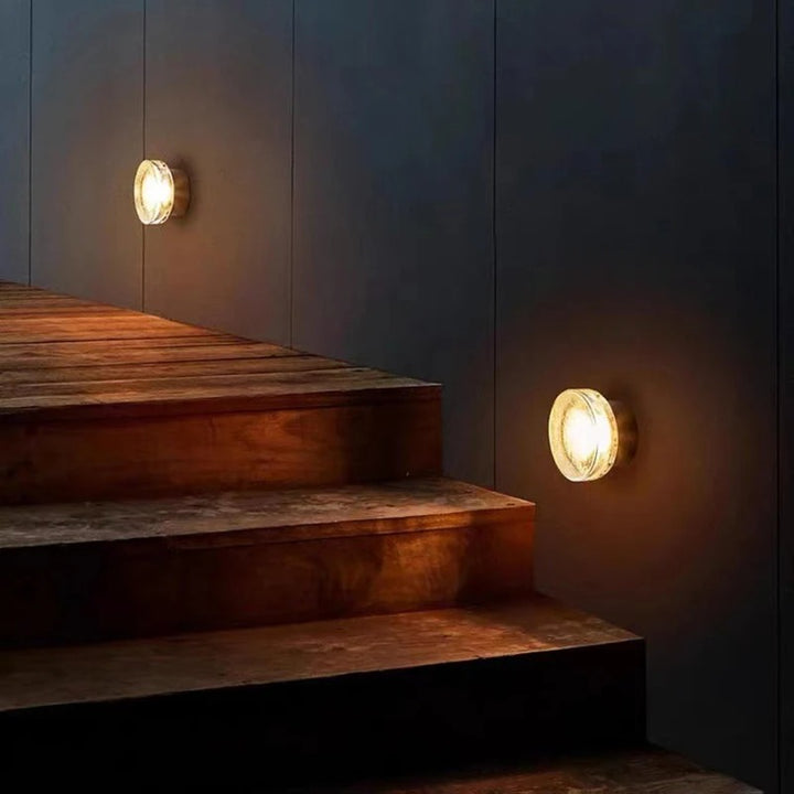 Wooden staircase with wall-mounted lights on a dark wall