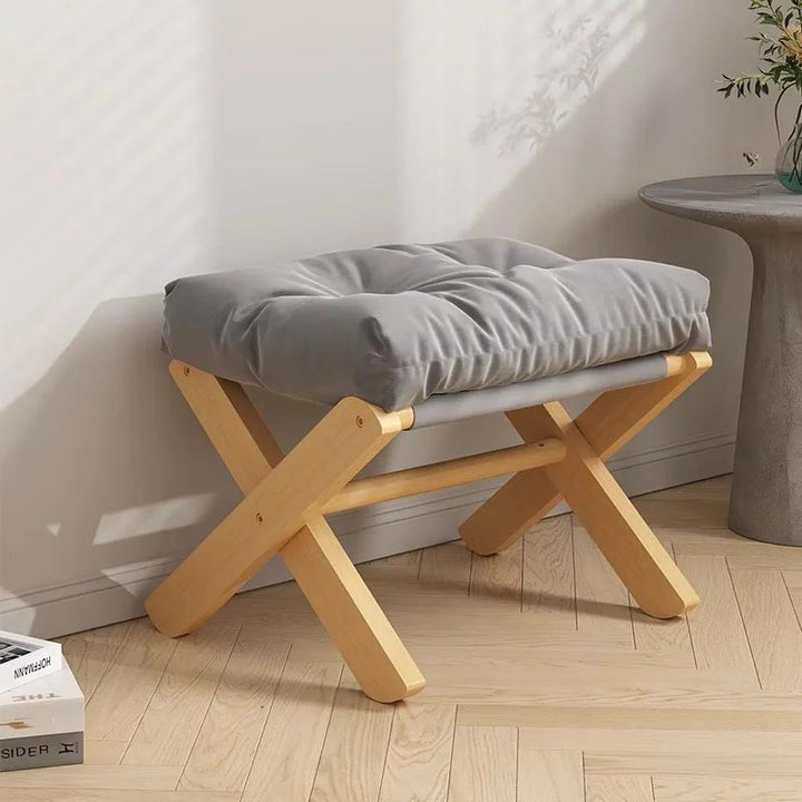 Foldable grey footstool with soft cushion placed near wall, natural wood base ideal for Nordic or Japandi-style UK interiors.