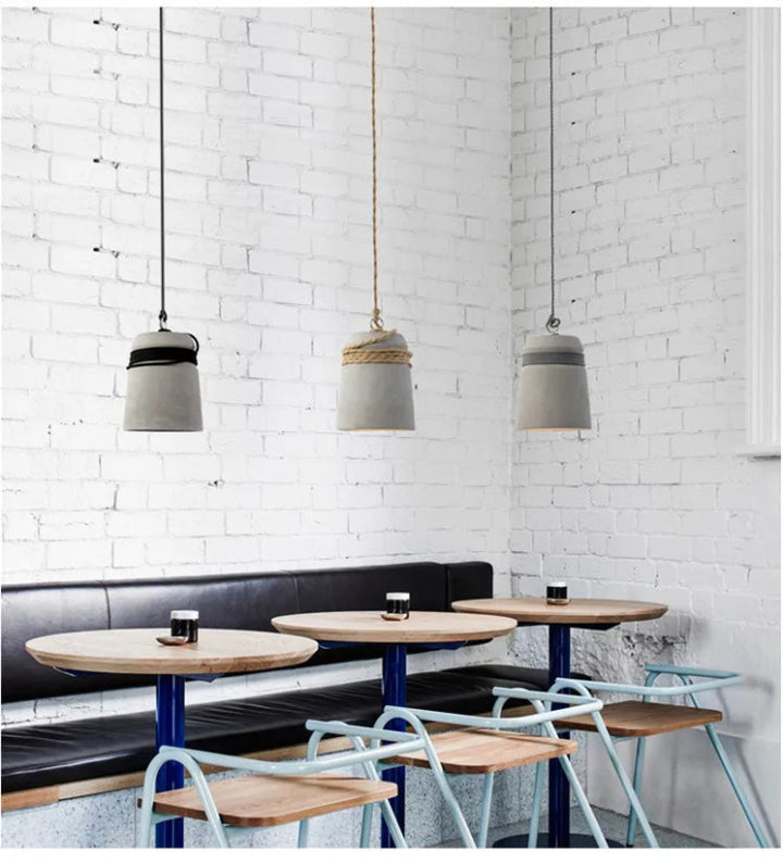 Modern cafe interior with pendant lights, tables, and chairs against a white brick wall.