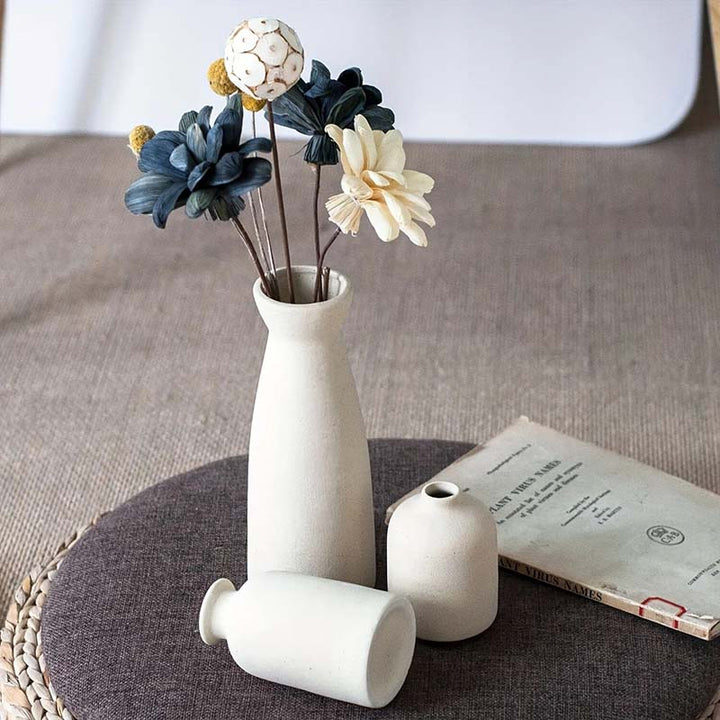 White vase with decorative flowers on a textured surface