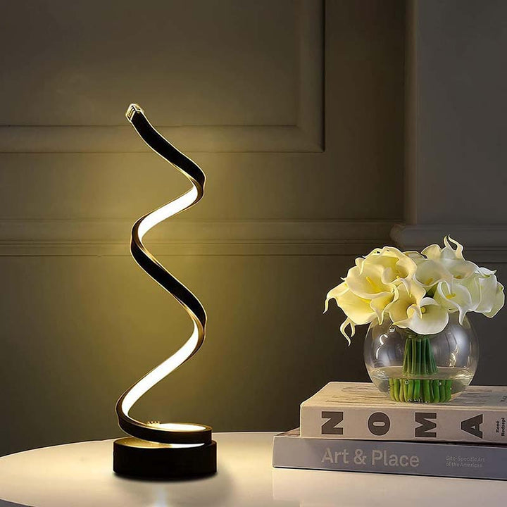 Modern LED table lamp with a decorative design on a surface with books and flowers.
