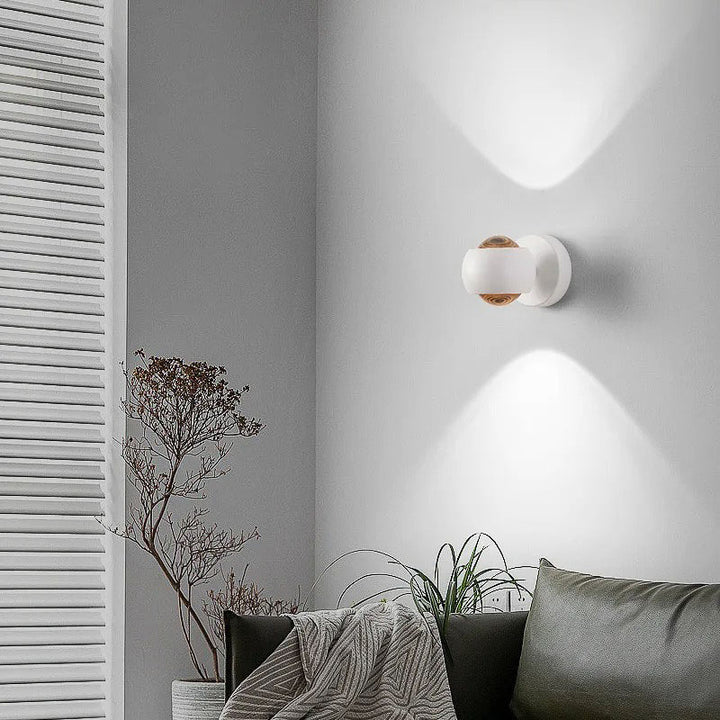 White adjustable LED wall light mounted in a modern living space, casting soft up-and-down lighting for a warm and elegant ambience. 