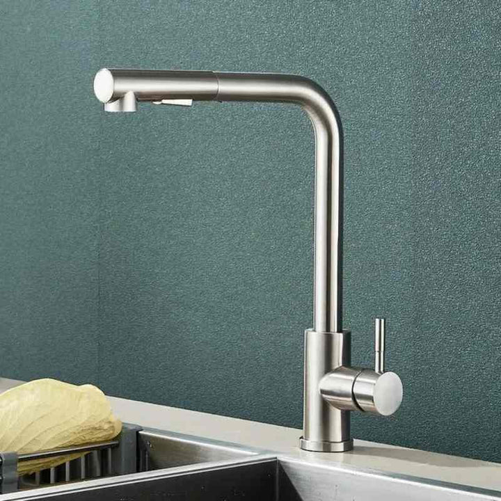 Stainless steel pull-out kitchen faucet with matte nickel finish above modern sink.