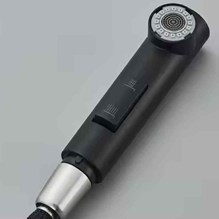 Close-up of matte black pull-out sprayer handle with dual spray mode button.