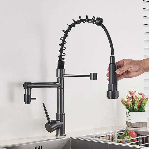 Matte black pull-down kitchen faucet with flexible spring neck, handheld sprayer rinsing fresh vegetables in sink.