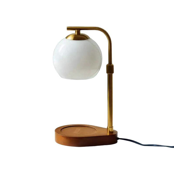 Table lamp with white globe shade and brass arm on a white background