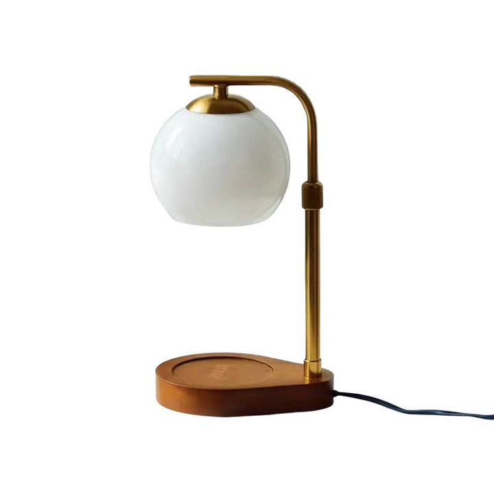 Table lamp with white globe shade and brass arm on a white background