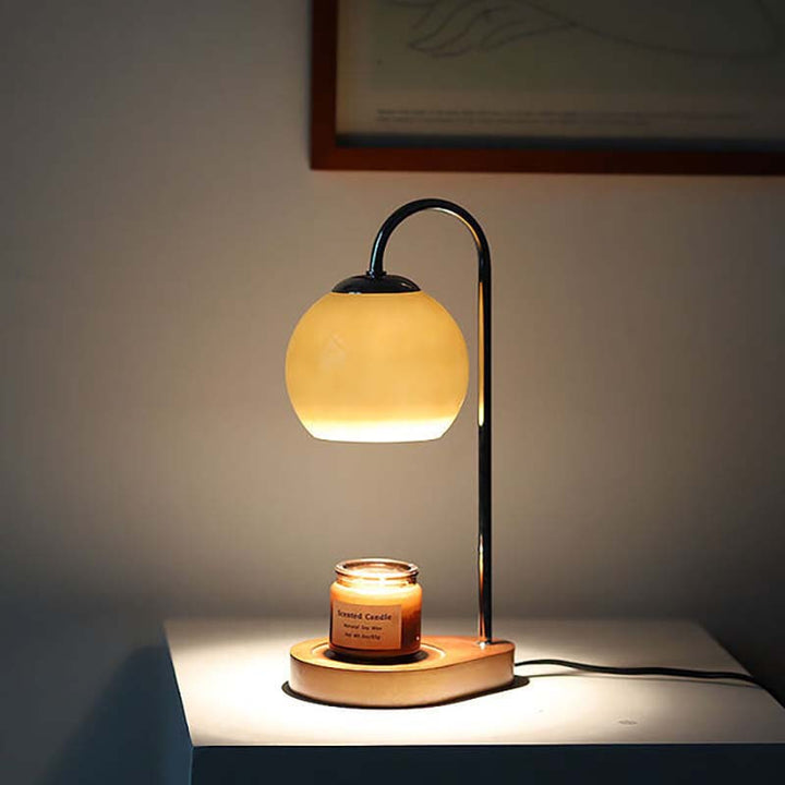 Table lamp with a candle on a wooden base in a dimly lit room.