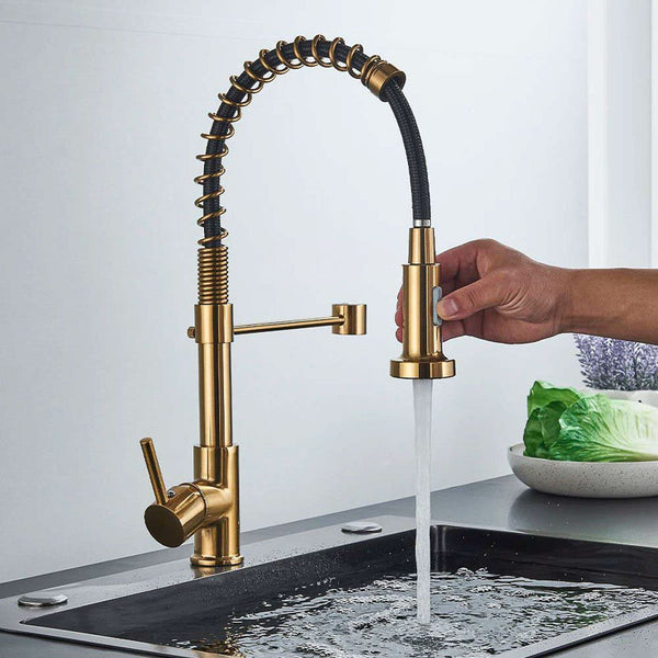 Gold kitchen tap with a hand turning on water, set against a neutral background.