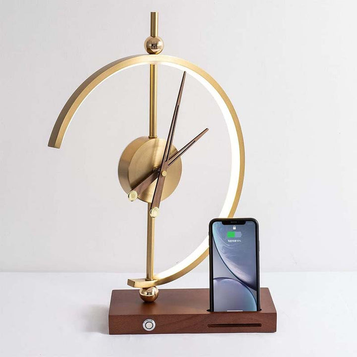 Gold desk clock with wooden base and smartphone dock on a white background