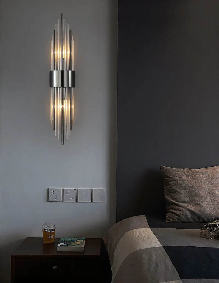 Crystal LED wall lamp in black mounted next to a bed, creating ambient lighting in a dark Nordic bedroom