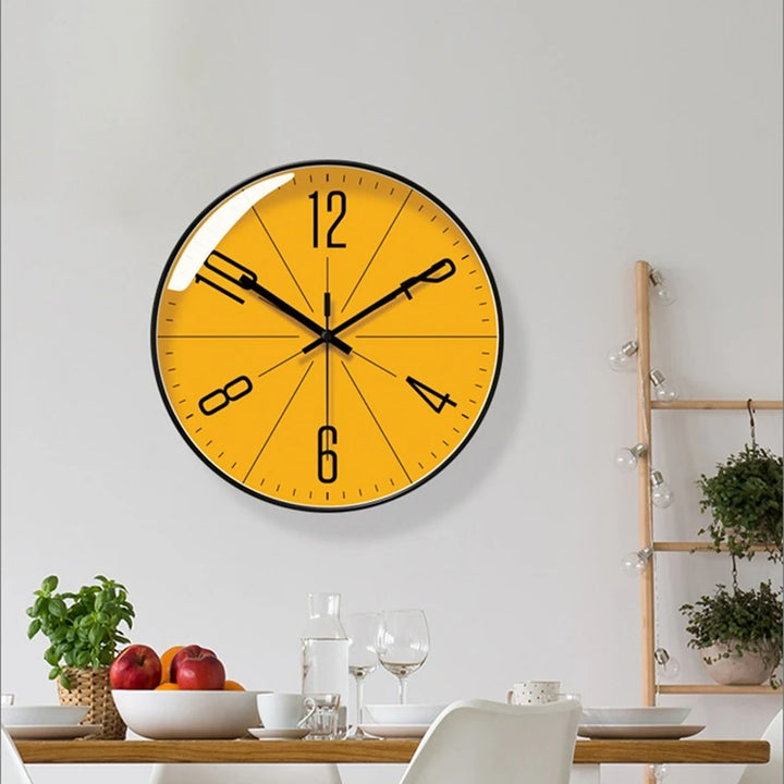 Yellow wall clock on a white wall above a dining table with fruit and glasses.