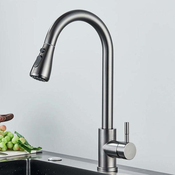 Brushed gunmetal grey pull-out kitchen faucet with single handle above sink.