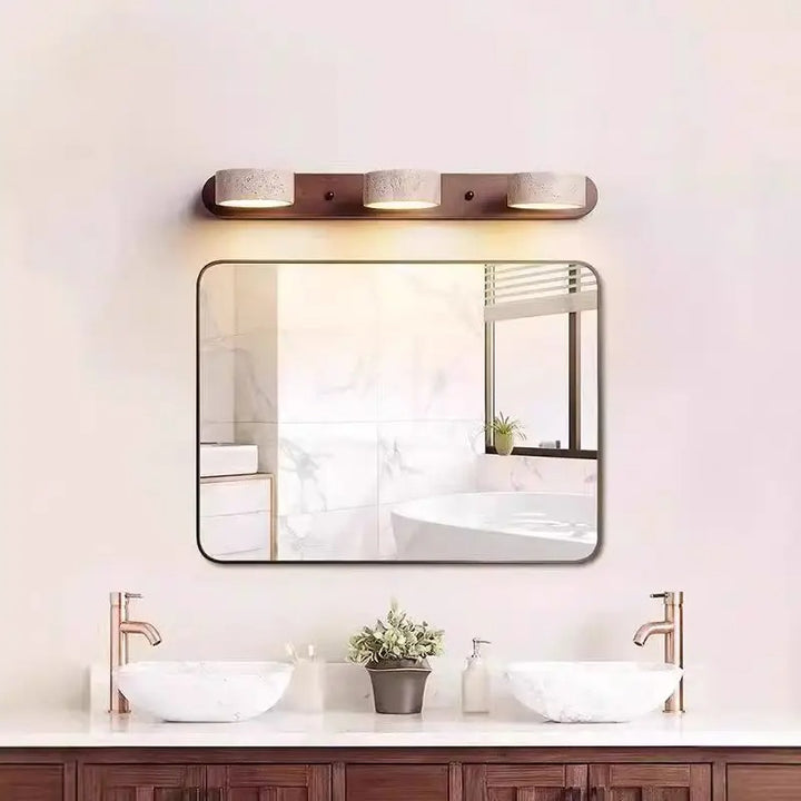 Bathroom vanity with mirror, lights, and decor on a light pink wall.