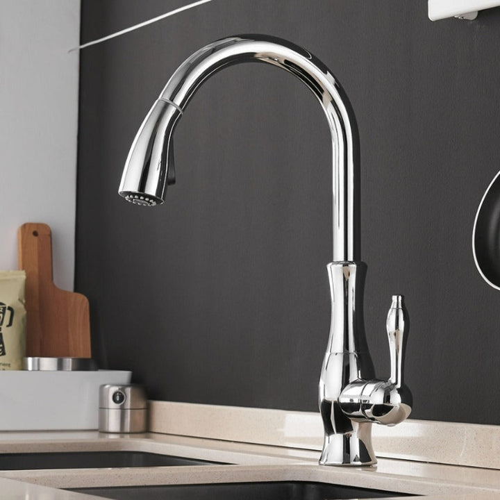 Chrome kitchen tap on a black backsplash with a sink.