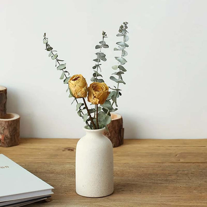 White vase with dried flowers on a wooden surface