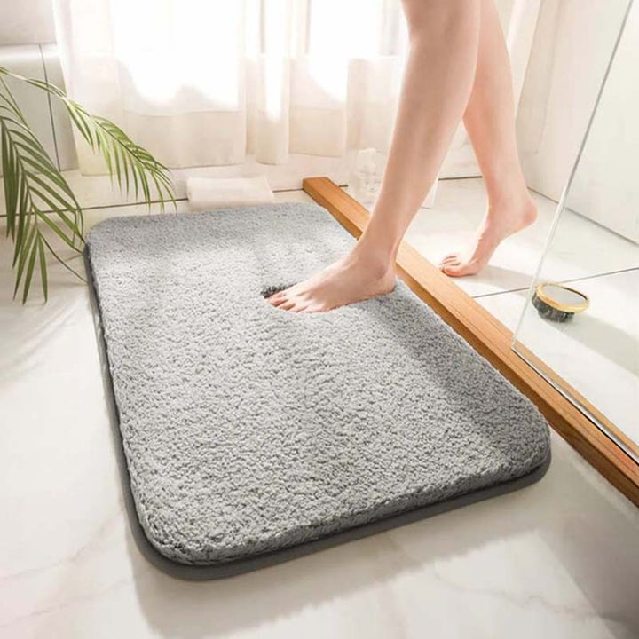 Person stepping onto a gray bath mat in a bathroom setting