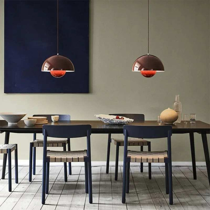 Dining room with a table, chairs, and pendant lights against a green wall.