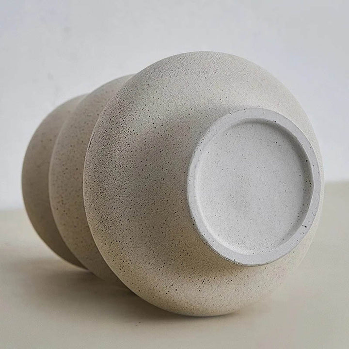 Modern ceramic vase with sculptural curves, styled on tray with magazine and tea in Nordic interior