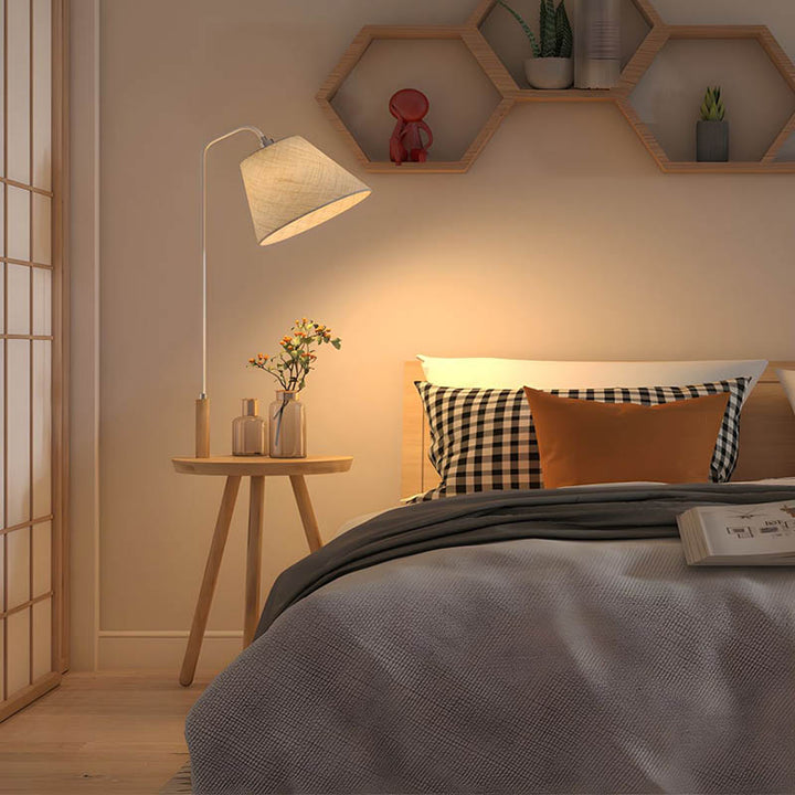Nordic floor lamp with table next to sofa, warm ambient lighting and natural wood, ideal for modern UK bedrooms