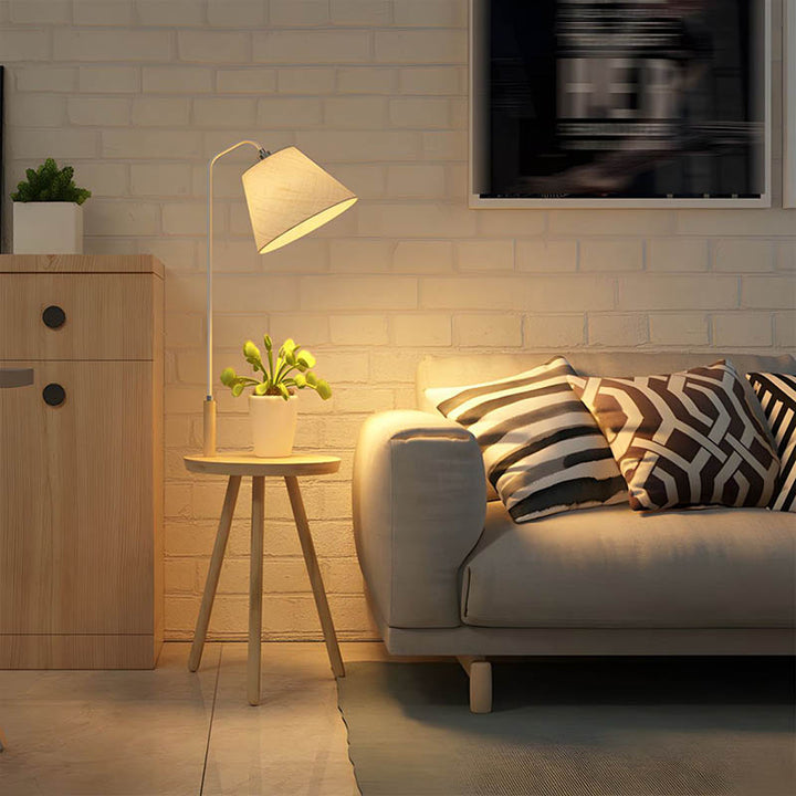 Nordic floor lamp with table next to sofa, warm ambient lighting and natural wood, ideal for UK lounge spaces.