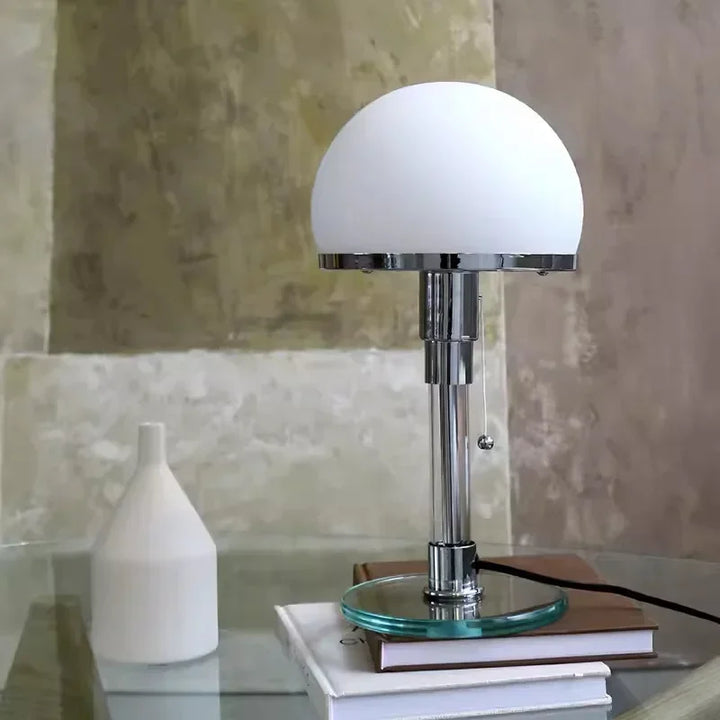 Modern Bauhaus table lamp with frosted glass dome and chrome base on glass desk