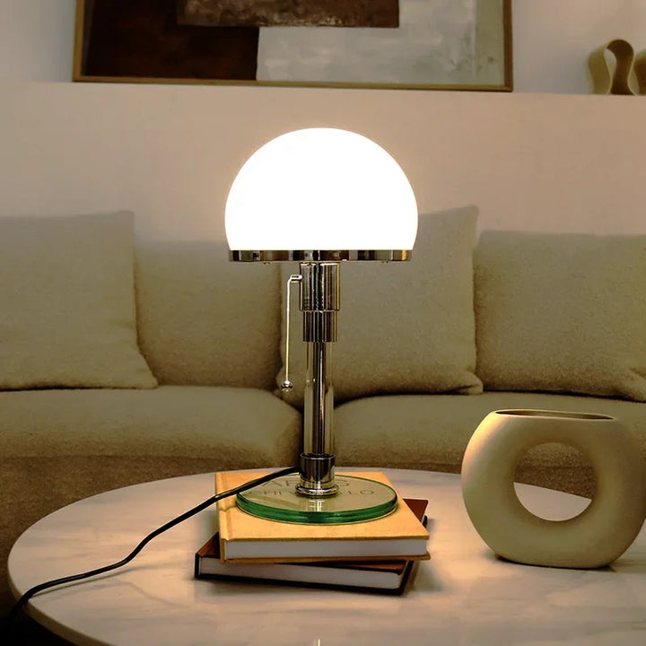 Elegant Bauhaus glass ball table lamp lit on marble coffee table in living room