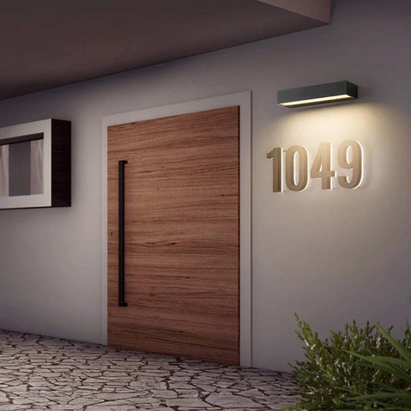 Modern house entrance with wooden door and outdoor Black Aluminum Wall Light illuminating house number.