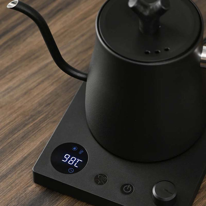 Black electric kettle on a wooden surface with digital temperature display