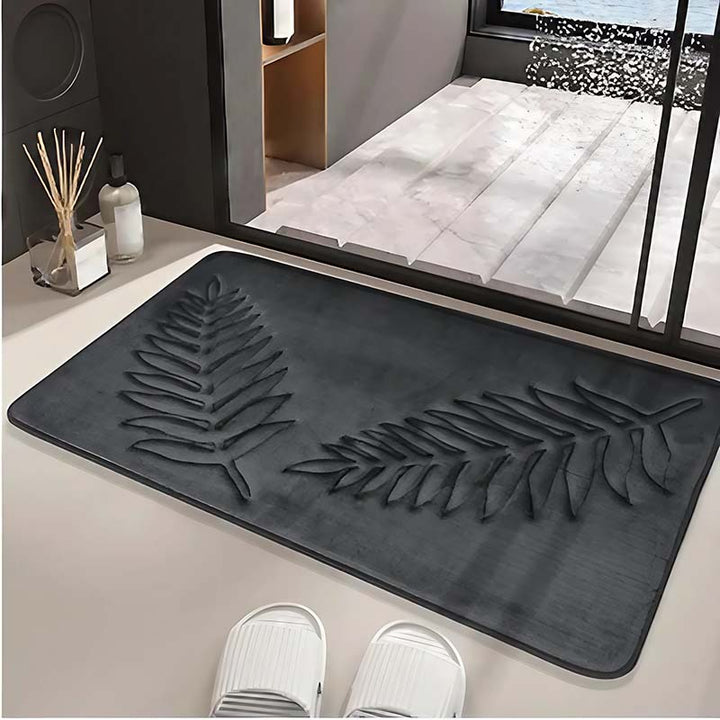 Black bathroom rug with leaf design on a floor next to a glass door