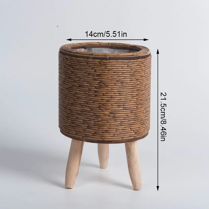 Cylindrical rattan plant basket with short wood legs, natural finish, styled with succulents, Nordic Essentials 